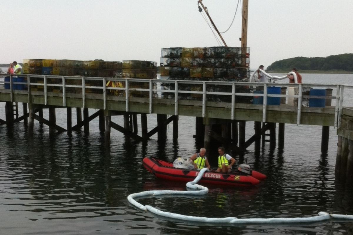 Labor Day Weekend 2014: Kennebunkport Firefighters use one of the department's rescue boats to deploy containment boom around an oil spill in Cape Porpoise Harbor. Maine DEP instituted clean-up activities involving the US Coast Guard and private contractors. 
